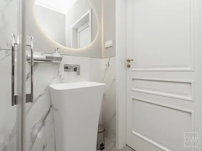 Łazienka z podświetlanym lustrem i rzeźbiarską umywalką wykończona spiekiem - apartament w Krakowie