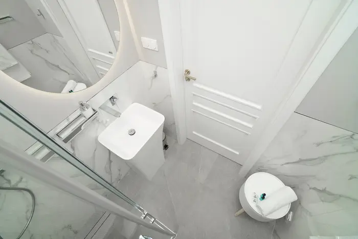 Widok z góry na łazienkę z okrągłym lustrem i wolnostojącą umywalką - apartament w Krakowie