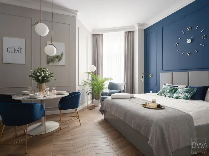 Studio z granatową ścianą, dużym zegarem i tapicerowanym łóżkiem - apartament w Krakowie