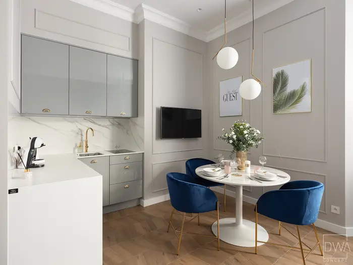 Aneks kuchenny z szarą zabudową połyskową i jadalnią w tle - apartament w Krakowie
