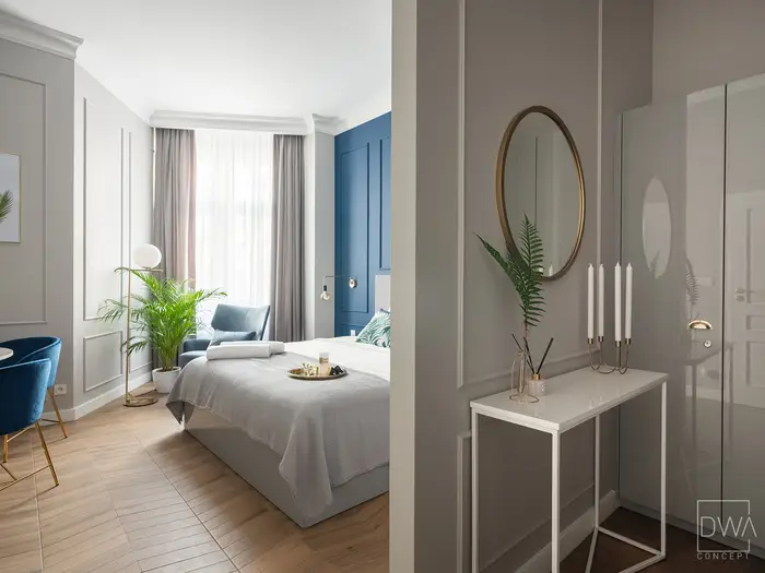 Konsola z okrągłym lustrem w złotej ramie i świecznikami - apartament w Krakowie