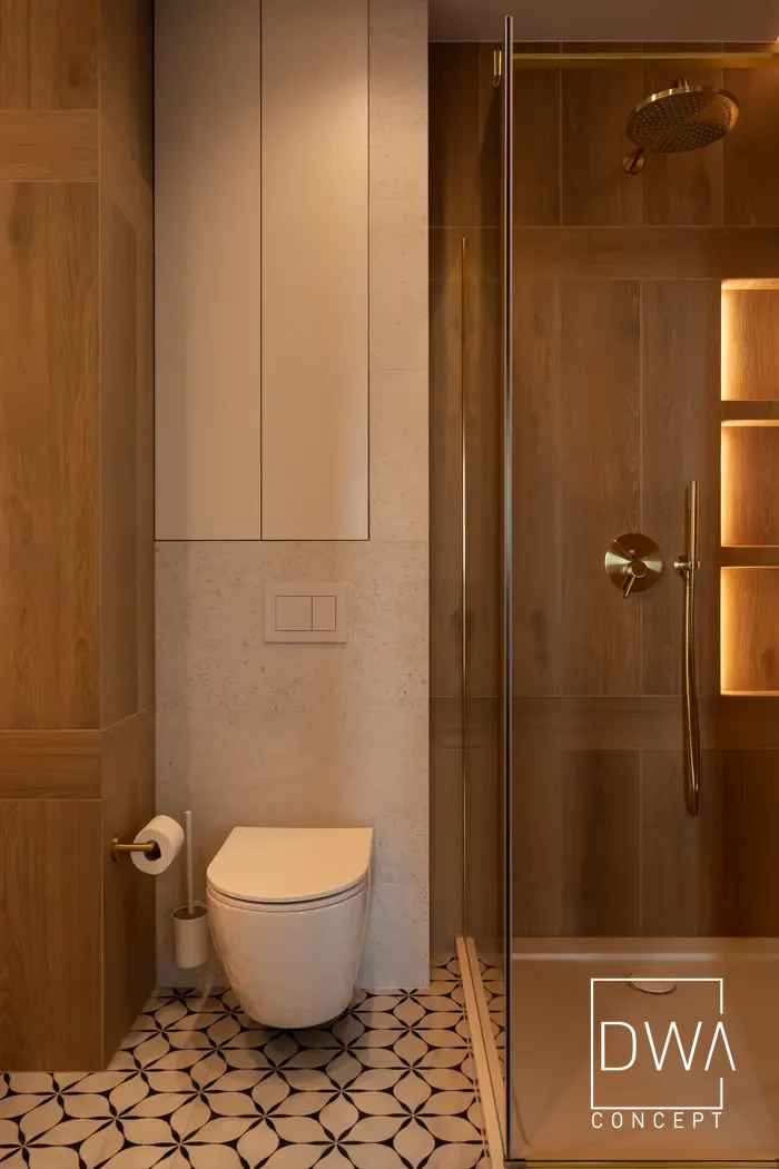 Łazienka z toaletą, wzorzystą podłogą i prysznicem za szklaną ścianką - apartament w Krakowie